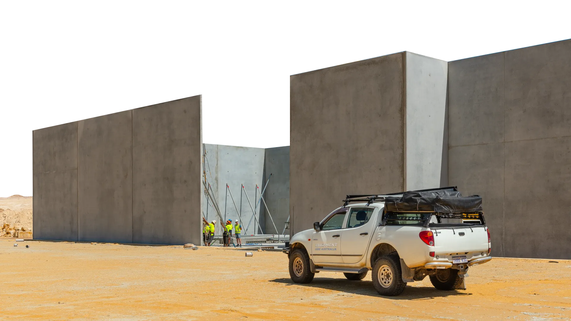 a ute parked in front of erected concrete panels using a crane